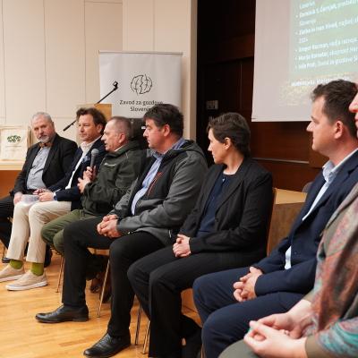 Udeleženci okrogle mize ob Mednarodnem dnevu gozdov 2026 - Gozd in ekonomija: z leve ustanovitelj Mizarstva Kos in muzeja Lesarius Jože Kos, predsednik Turistične zveze Slovenije Dominik S. Černjak, revirni gozdar ZGS Jože Prah, najbolj skrbna lastnika gozda 2024 Zlatka in Ivan Vivod, vodja razvoja in prodaje v podjetju Tajfun Gregor Racman ter Marija Komatar iz Skupnosti Herbalist.